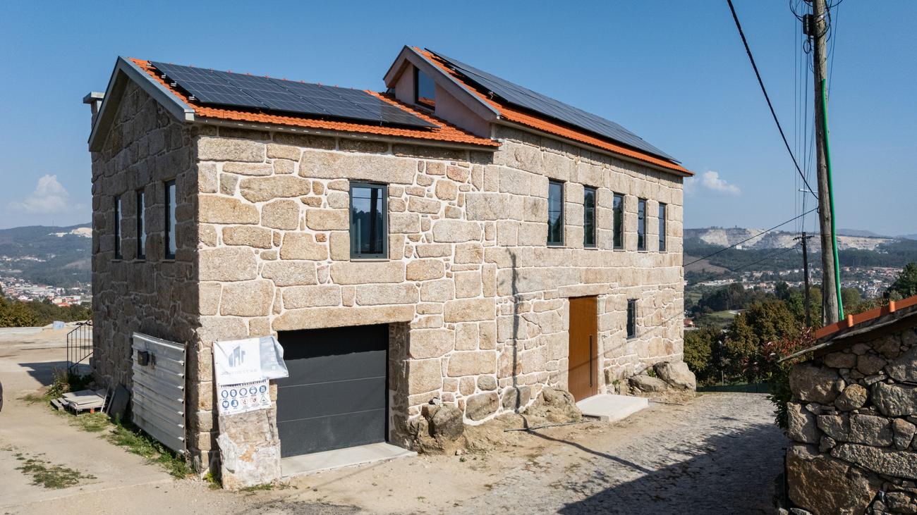 Casa de pedra com painéis solares e portão de garagem — Casas da Giesteira, Termas de São Vicente, Penafiel