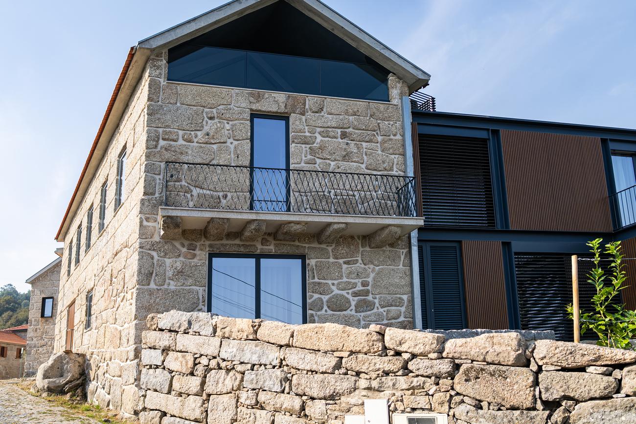 Fachada em granito com varanda e ampliação em madeira e vidro — Casas da Giesteira, Termas de São Vicente, Penafiel