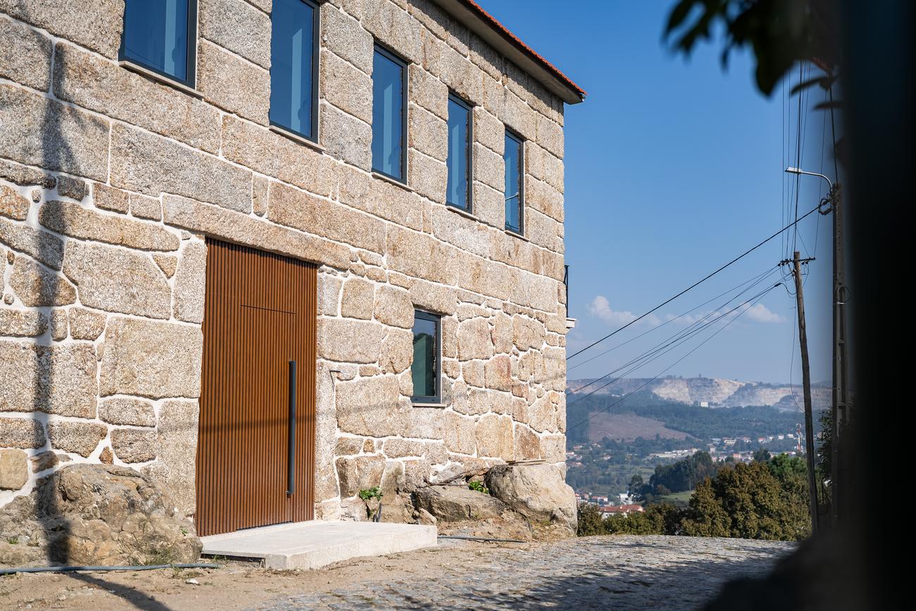 Grande porta em madeira numa fachada de granito — Casas da Giesteira, Termas de São Vicente, Penafiel