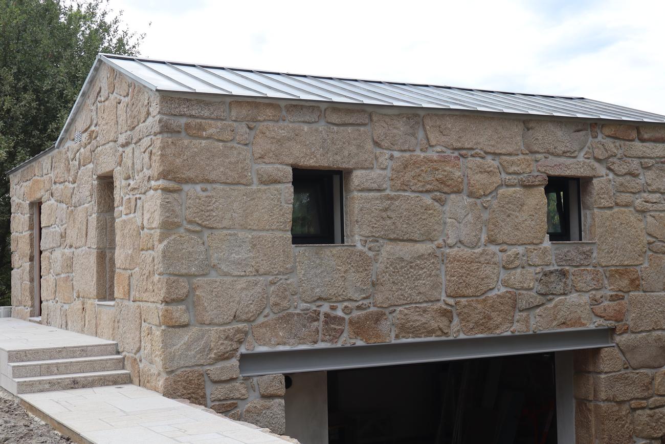 Reabilitação da Quinta de Luzim, Penafiel — frente da casa de pedra com cobertura metálica e rampa em pedra
