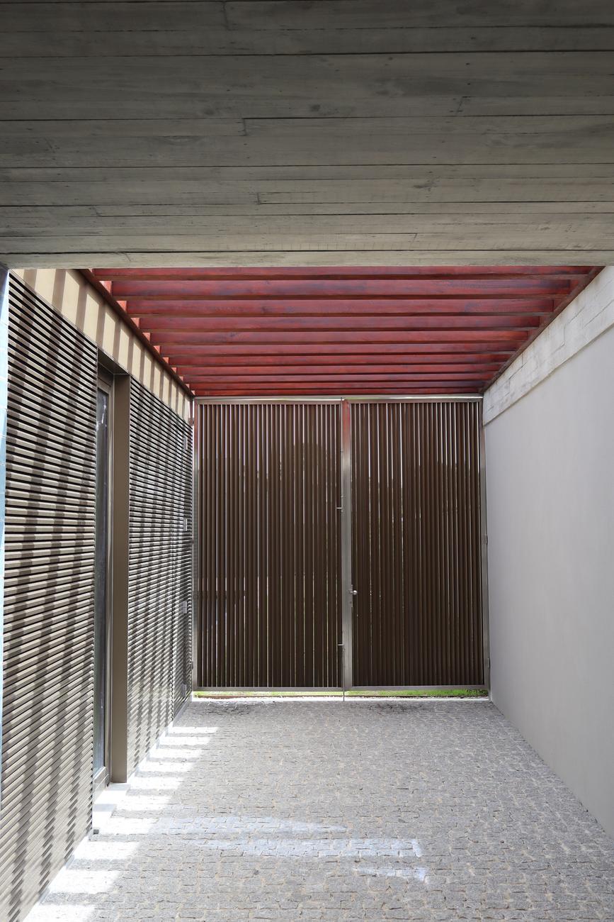 Pátio de entrada com ripas de madeira e teto em betão — Casa das Centieiras, São Félix da Marinha