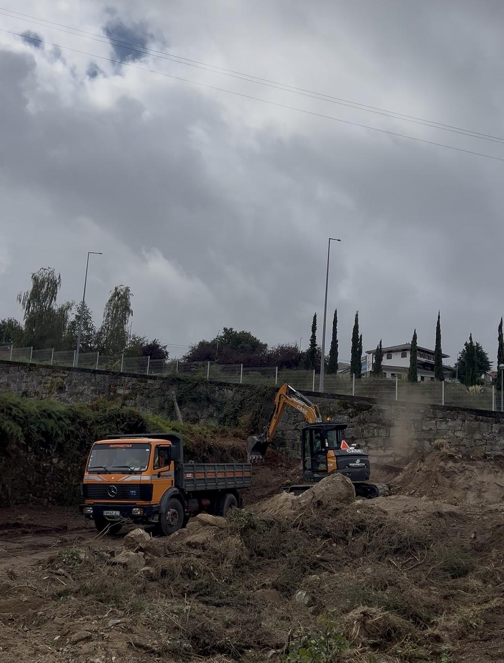 Camião basculante e escavadora em obra — terraplanagem e movimentação de terras